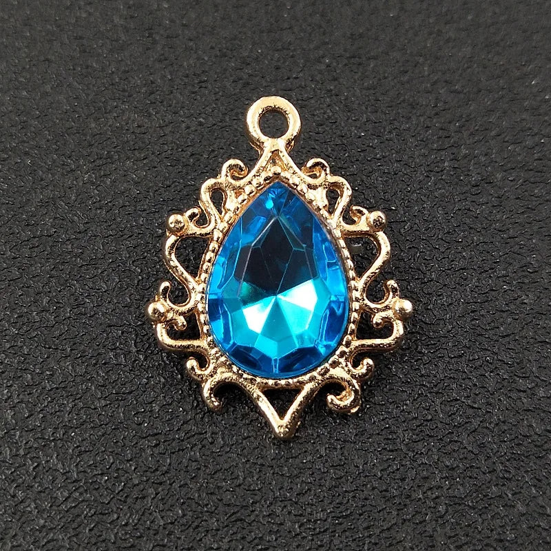 Gold plated water droplet charm featuring a brilliant blue crystal rhinestone set in an ornate flower design.