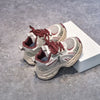 A pair of red and beige breathable mesh kids running sneakers resting on a white box.
