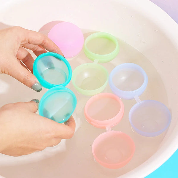 A hand is holding several colorful reusable silicone water balloons in a white bowl.