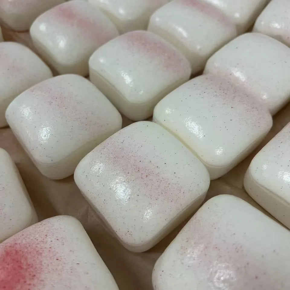 A close-up view of several white squishy stress relief cubes with pink speckles.