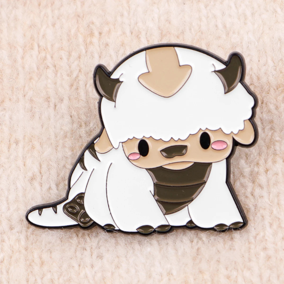 A cute enamel pin featuring a white horned creature with brown accents.