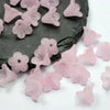 Pink frosted acrylic flower beads scattered on a dark surface