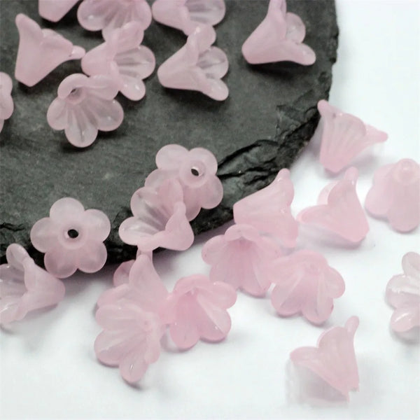 Cuentas acrílicas de flor con frosting rosa esparcidas sobre superficie oscura