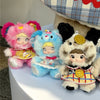 Three fluffy collectible dolls with pink, blue, and white fur are displayed next to a plaid hat.