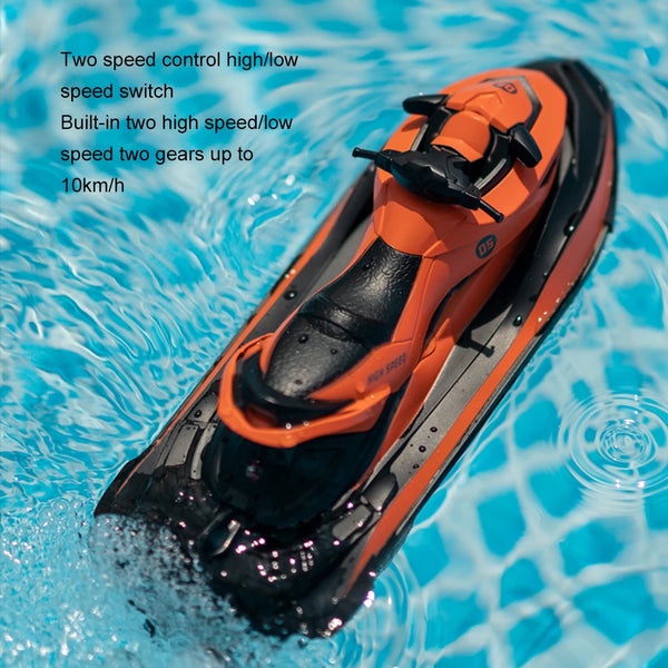 An orange high-speed RC jet ski boat is shown moving through clear blue water.