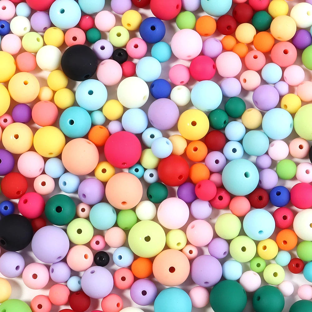 A close-up view of a large assortment of colorful matte acrylic beads in various shades including pink, yellow, blue, and gre