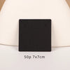 A black square jewelry display card is shown on a light beige surface.