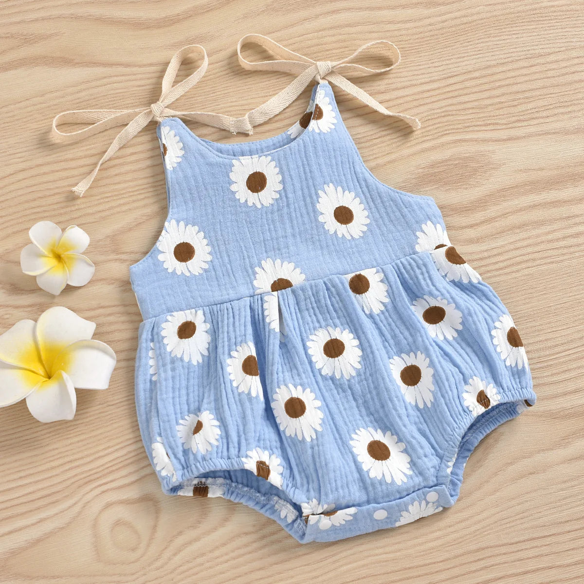 Light blue cotton romper for a baby girl with white daisy floral print and adjustable ties