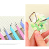 A hand uses precision stainless steel tweezers to place small decorative elements onto a translucent surface.