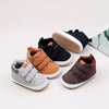 A collection of soft PU leather baby first walker shoes in brown, gray, and black with anti-slip soles.