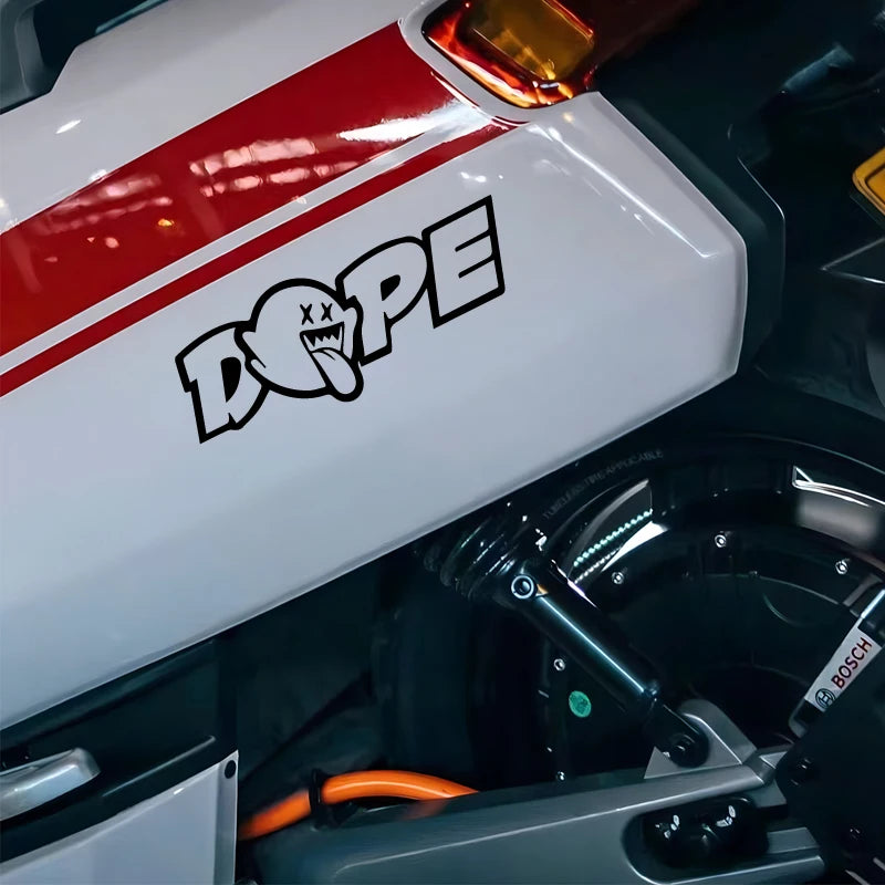 A close-up of a white panel with a red stripe and the black DOPE decal sticker on a vehicle component.