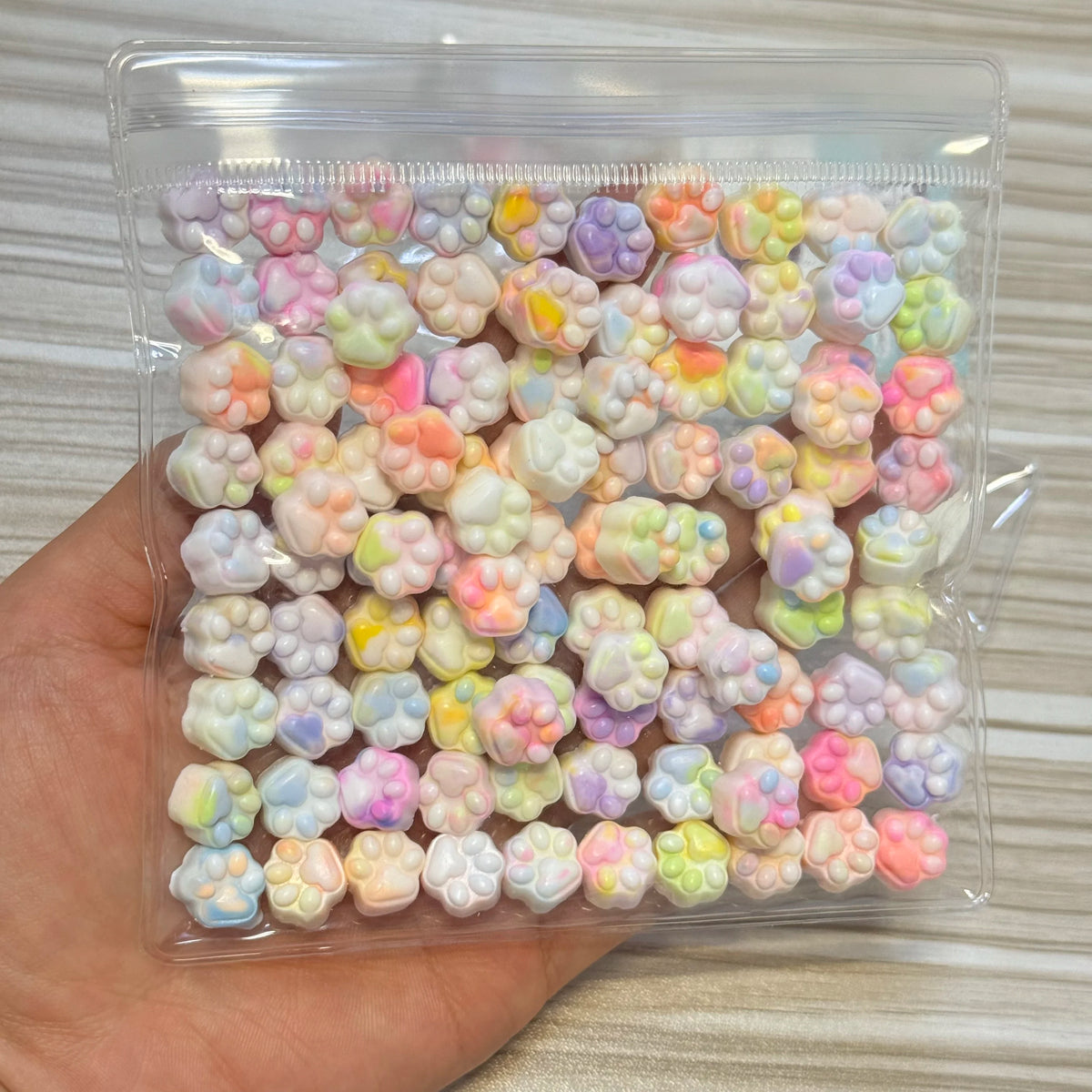 A clear plastic bag filled with numerous pastel-colored, squishy cat paw shaped fidget toys.