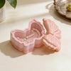 A pink silicone resin mold shaped like a bowknot with a lid, featuring a striped pattern and a pearl necklace inside.