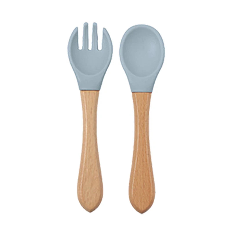Une paire d'ustensiles à manger en silicone bleu clair, avec fourchette et cuillère, et manches en bois.
