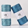 Spool of metallic teal yarn for knitting and crochet with a label reading attitude macrame