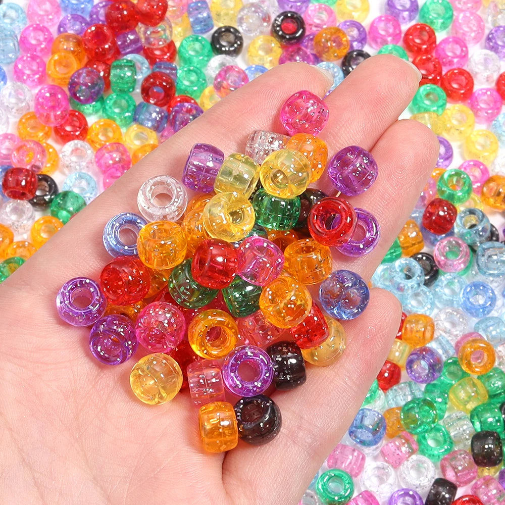 A hand holds a pile of 200 colorful pony beads in various shades of red, green, yellow, and purple.
