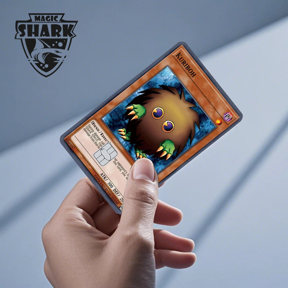A hand holds a Magic Shark card featuring the Kuriboh monster, an anime dragon PVC card skin sticker.