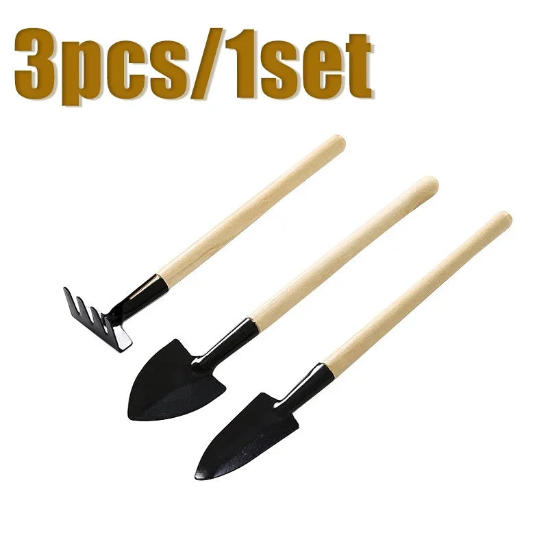 A set of three mini gardening tools with wooden handles and black blades.