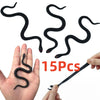 A hand is holding a black rubber snake prop with a thin stick, showing the flexible, realistic texture of the snake.