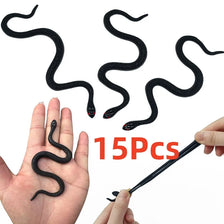 A hand is holding a black rubber snake prop with a thin stick, showing the flexible, realistic texture of the snake.