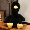 A black plush toy shaped like a duck with yellow accents, displayed on a wooden surface.