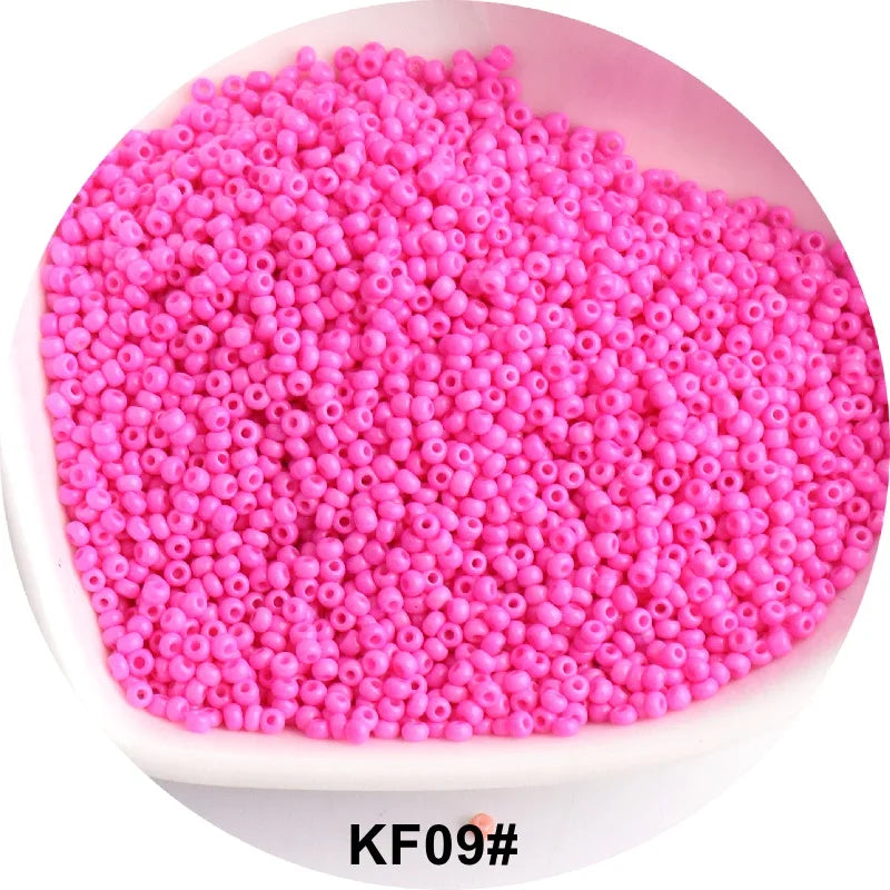 A pile of bright pink 1.5mm solid glass seed beads for jewelry and craft.