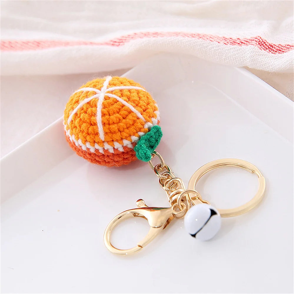 Handmade crochet orange fruit keychain pendant with green accent on a gold chain