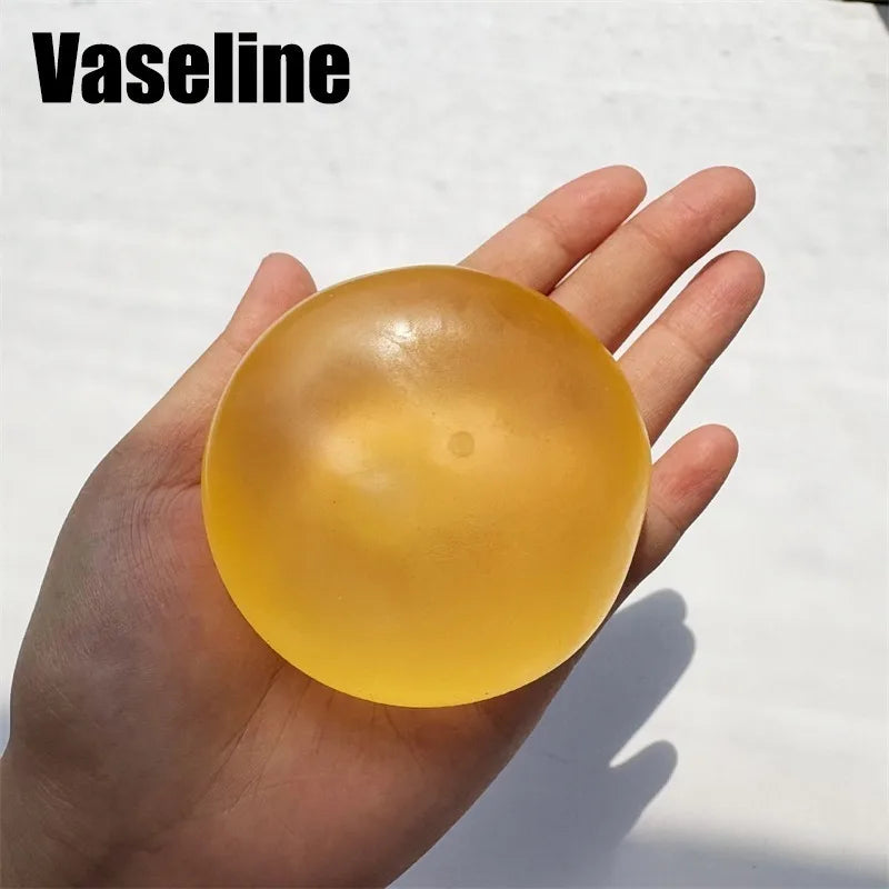 A hand holds a translucent yellow silicone fidget ball for stress relief and focus.