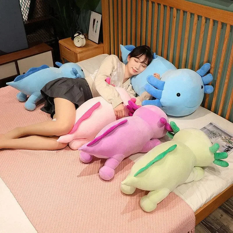 A collection of large colorful axolotl plush pillows and stuffed animals resting on a pink surface.