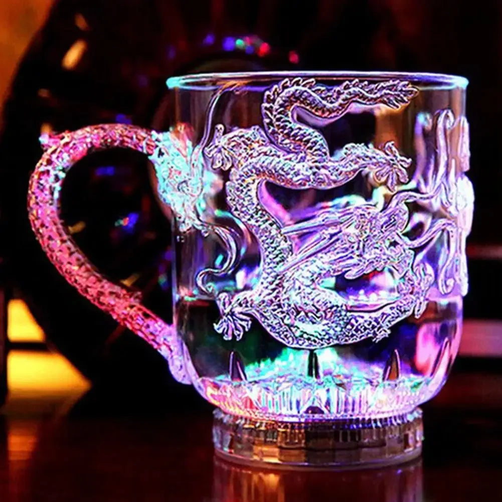 A clear mug featuring an intricately detailed dragon design that glows with a vibrant purple and blue light.