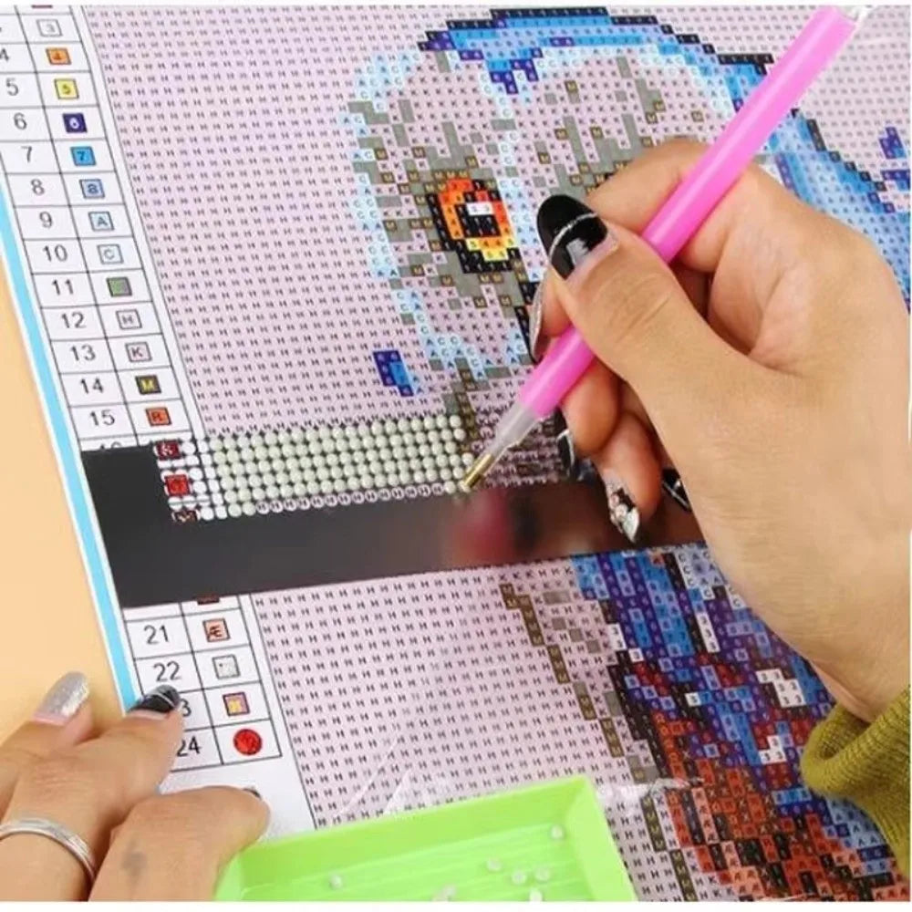 A hand holds a pink pen drawing on a diamond painting grid on a tablet screen.