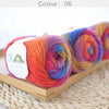A collection of hand-dyed rainbow merino wool yarn skeins in various vibrant colors displayed on a wooden tray.