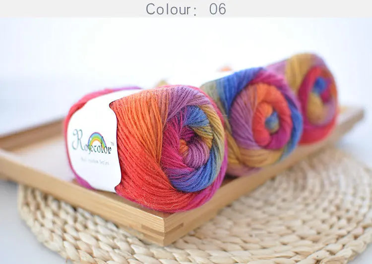 A collection of hand-dyed rainbow merino wool yarn skeins in various vibrant colors displayed on a wooden tray.