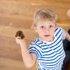 A young boy holds a realistic, soft brown squishy toy resembling fake poop.