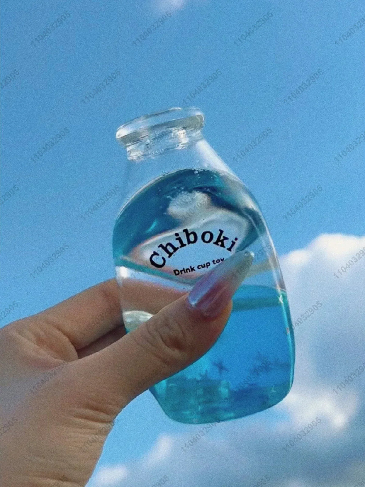 A hand holds a clear blue bottle labeled Chiboki, which is a fruit bottle stress ball or squishy fidget toy.