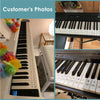 A close-up view of a white piano keyboard with note stickers placed on the black keys.