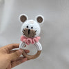 A handmade stuffed animal resembling a bear with large ears and a pink ruffle, held in a person's hand.