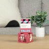 A stack of pink and black card game boxes titled TALES, featuring conversation starter cards, sits on a wooden table.