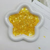A white, heart-shaped mold filled with bright yellow glitter acrylic filler for nail art and DIY crafts.