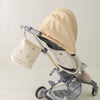 A beige quilted baby diaper caddy organizer with stroller straps is shown on a gray stroller.