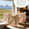 A set of white ceramic candle molds shaped like horses with Celtic knot designs displayed on a windowsill.