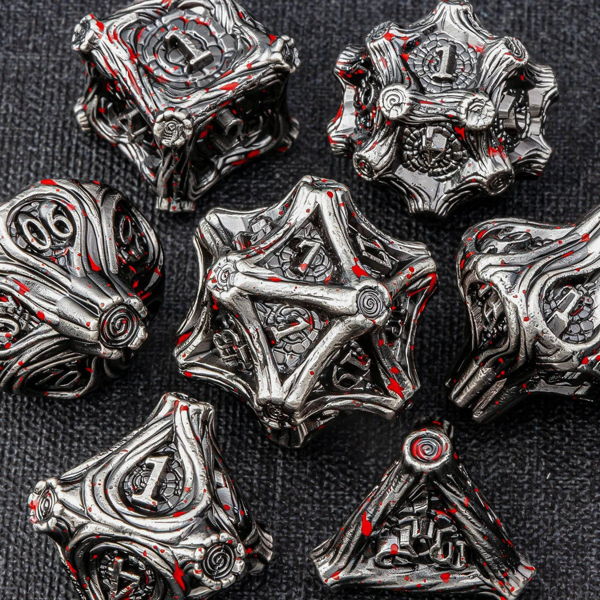 A collection of intricate, metallic dice made from zinc alloy, featuring a dark silver finish and red accents.