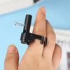 A hand holds a black finger ring launcher fidget toy with a silver screw visible.