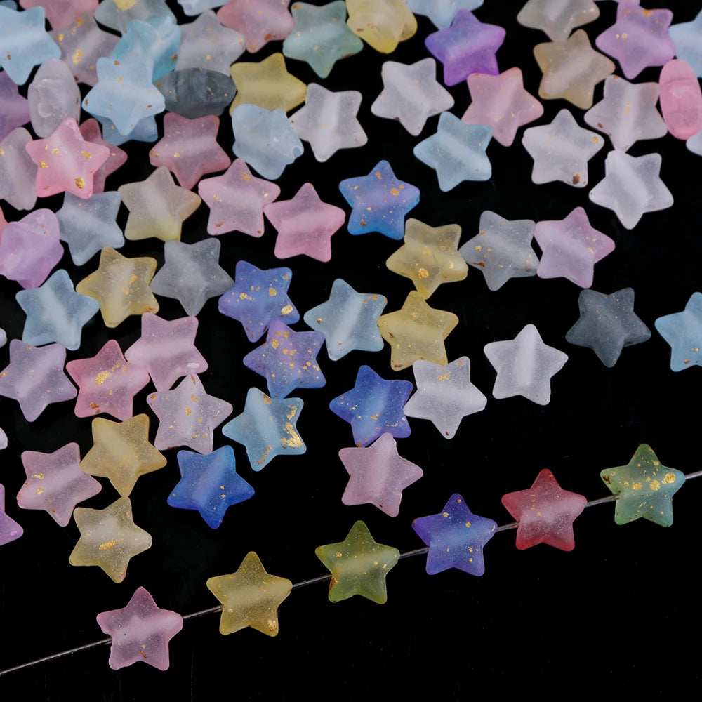 A collection of colorful transparent star acrylic beads in various pastel shades scattered on a dark surface.