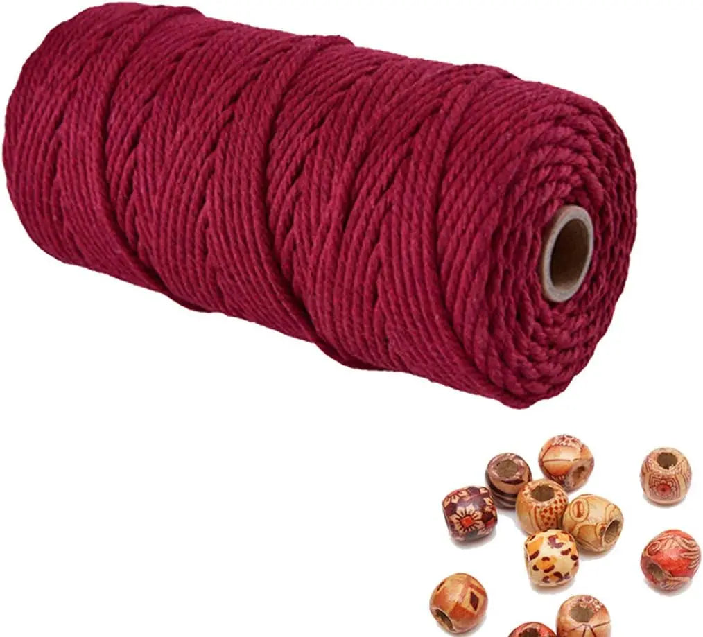 A spool of deep red natural cotton macrame rope used for crafts and decor.