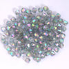 A pile of small, faceted, iridescent glass beads in various shades of green and purple.