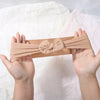 Three soft beige stretch baby headbands with bows are held in open hands against a white background.