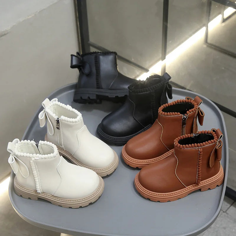 A collection of black and tan faux leather winter boots for kids, including ankle boots and lace-up styles.