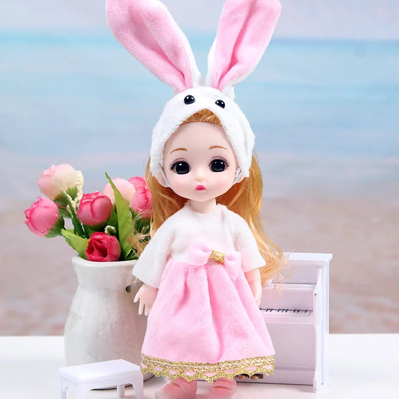 A 17cm articulated princess doll with a white and pink dress-up outfit standing in front of a blurred ocean background.