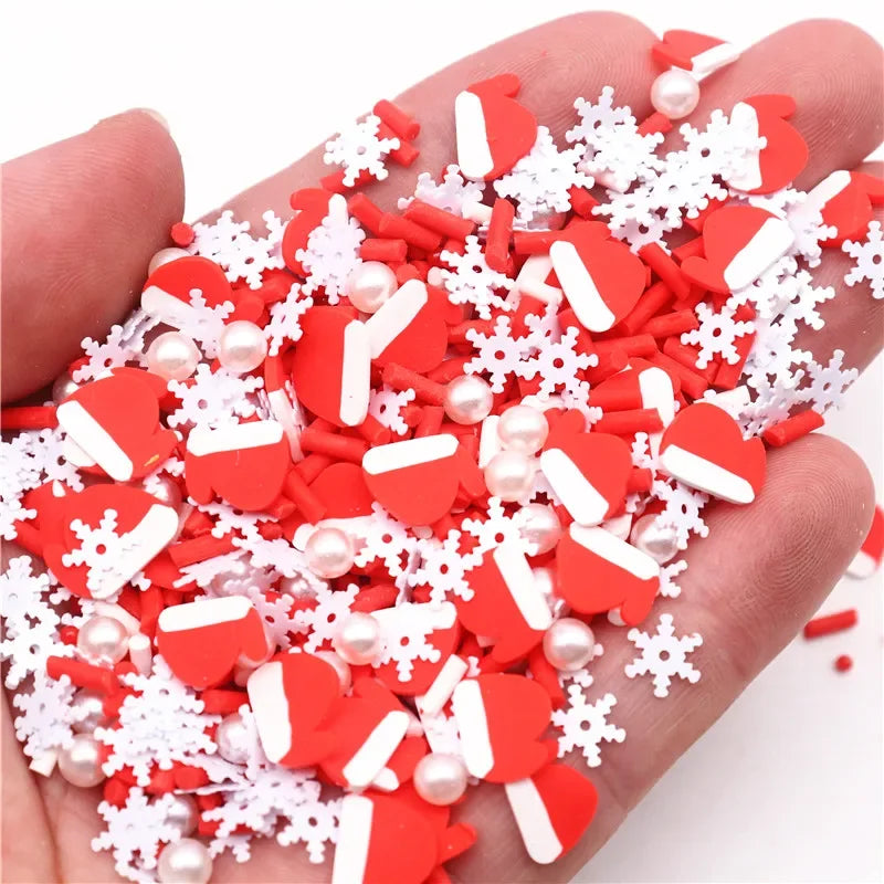 A hand holds a pile of red and white heart-shaped polymer clay slices and snowflake decorations for DIY crafts.